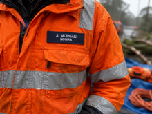 Load image into Gallery viewer, Person wearing an orange safety jacket with 'J. Morgan Nowra' name tag in a blurred outdoor setting.