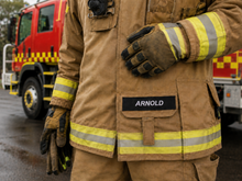 Load image into Gallery viewer, Firefighter in protective gear with 'Arnold' branding, standing in front of a fire truck.
