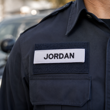 Load image into Gallery viewer, Navy blue uniform with a patch labeled 'JORDAN' on a blurred background
