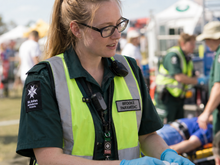 Load image into Gallery viewer, Paramedic wearing a high-visibility vest with 'St John Ambulance' logo and name tag, attending to a patient.
